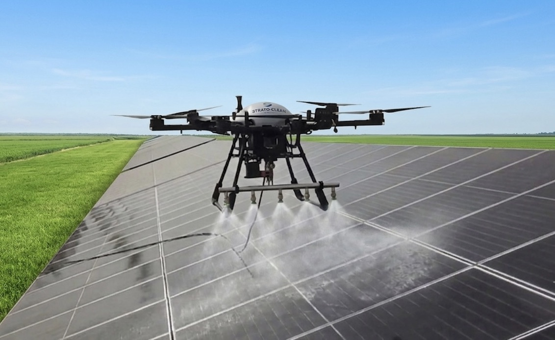 StratoClean drone soft-washing a ground-mounted utility-scale solar panel array in an open field — touchless, no water trucks, no manned crews on the array